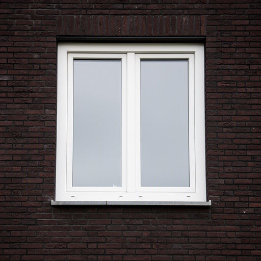 Close-up kunststof kozijn wit op donkere bakstenen gevel Drunen